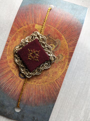 Maroon kasuti rakhi with traditional embroidered design